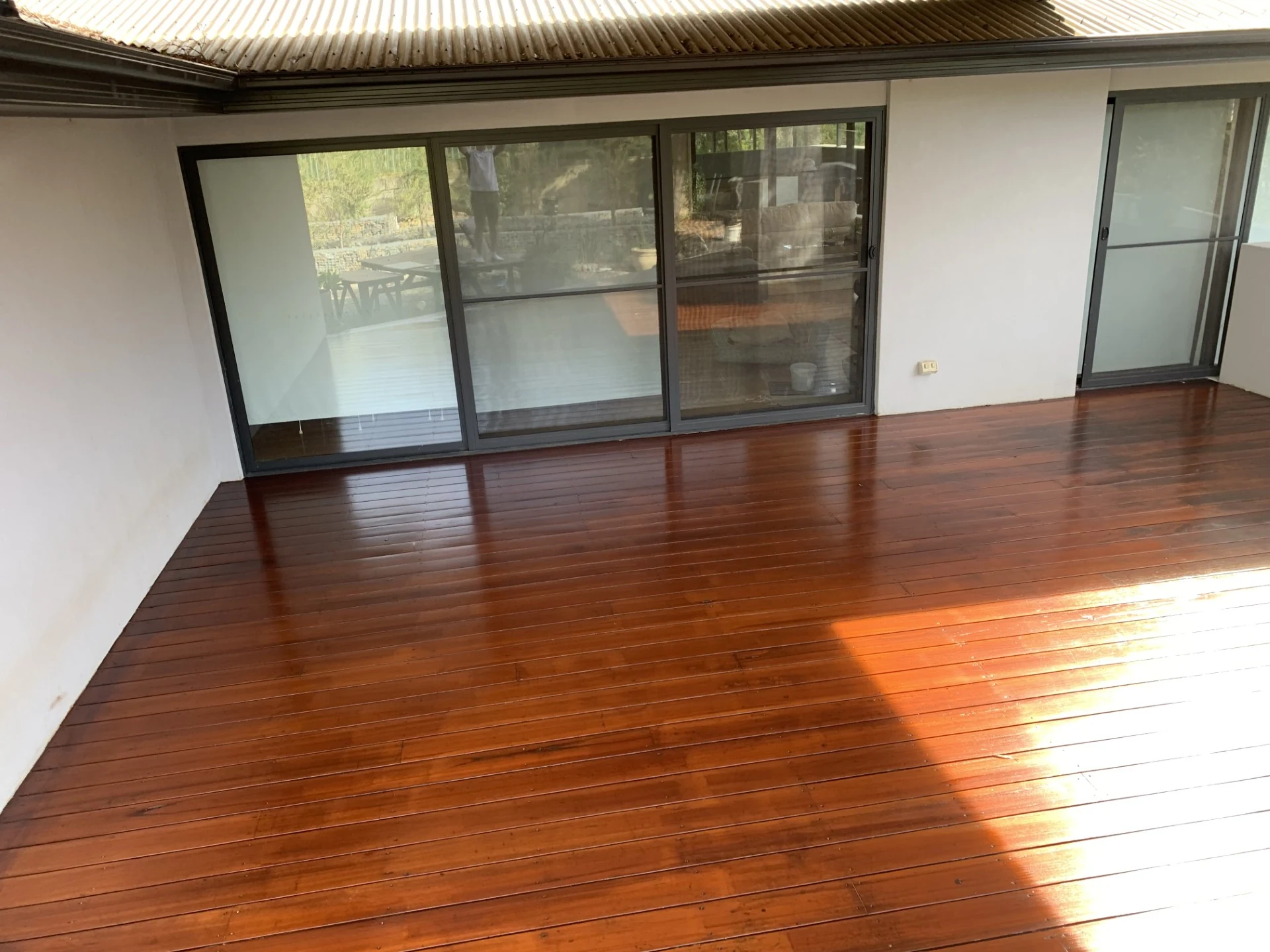 Restored timber deck with a rich polished finish beside wide sliding doors