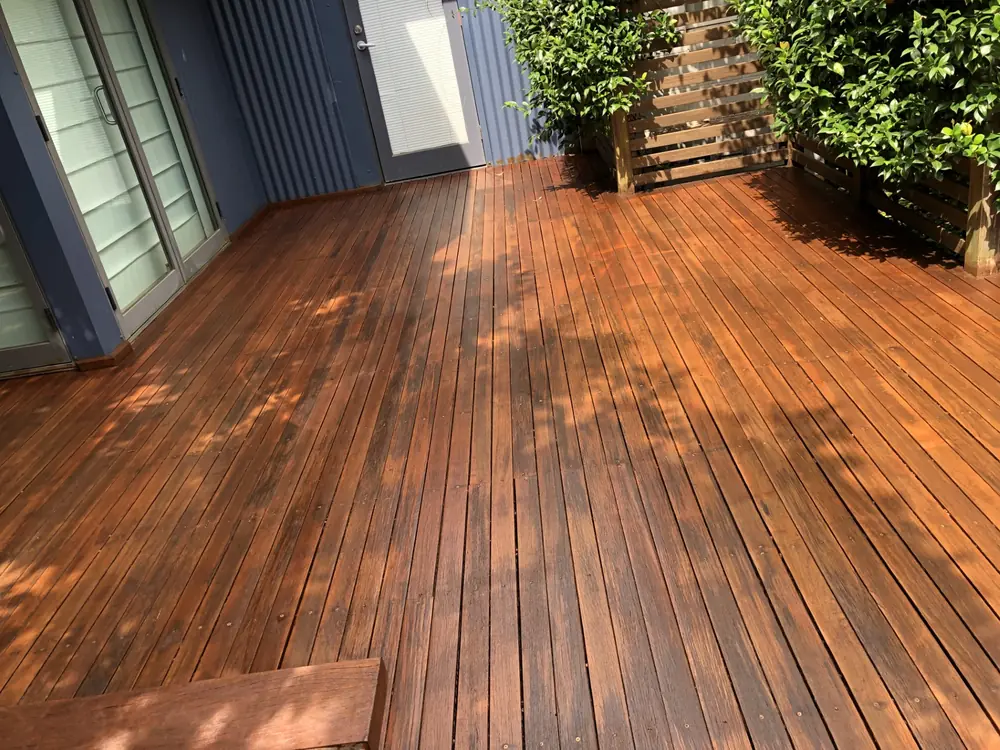 Wide restored timber deck with a rich warm finish beside a home exterior