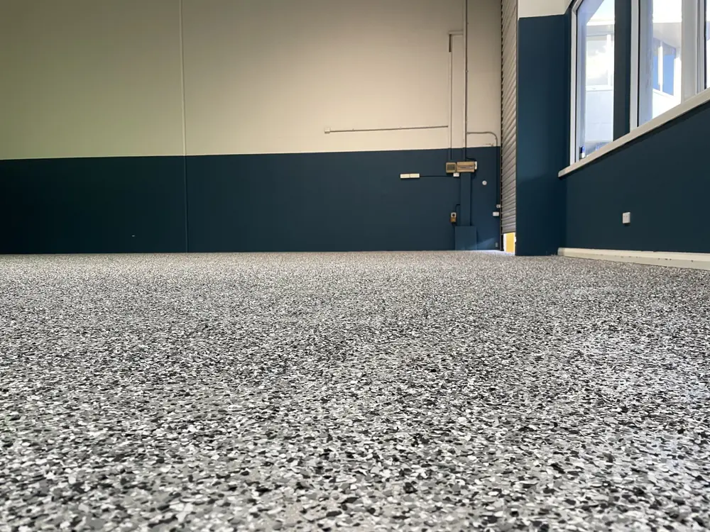 Finished speckled epoxy floor meeting dark painted workshop walls