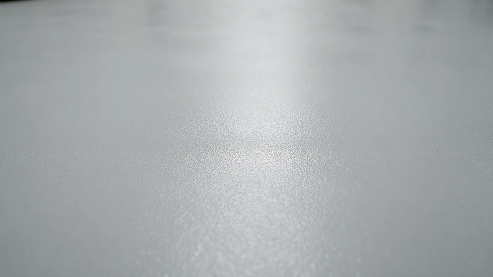 Close-up of a smooth light-grey epoxy floor with a soft reflective sheen