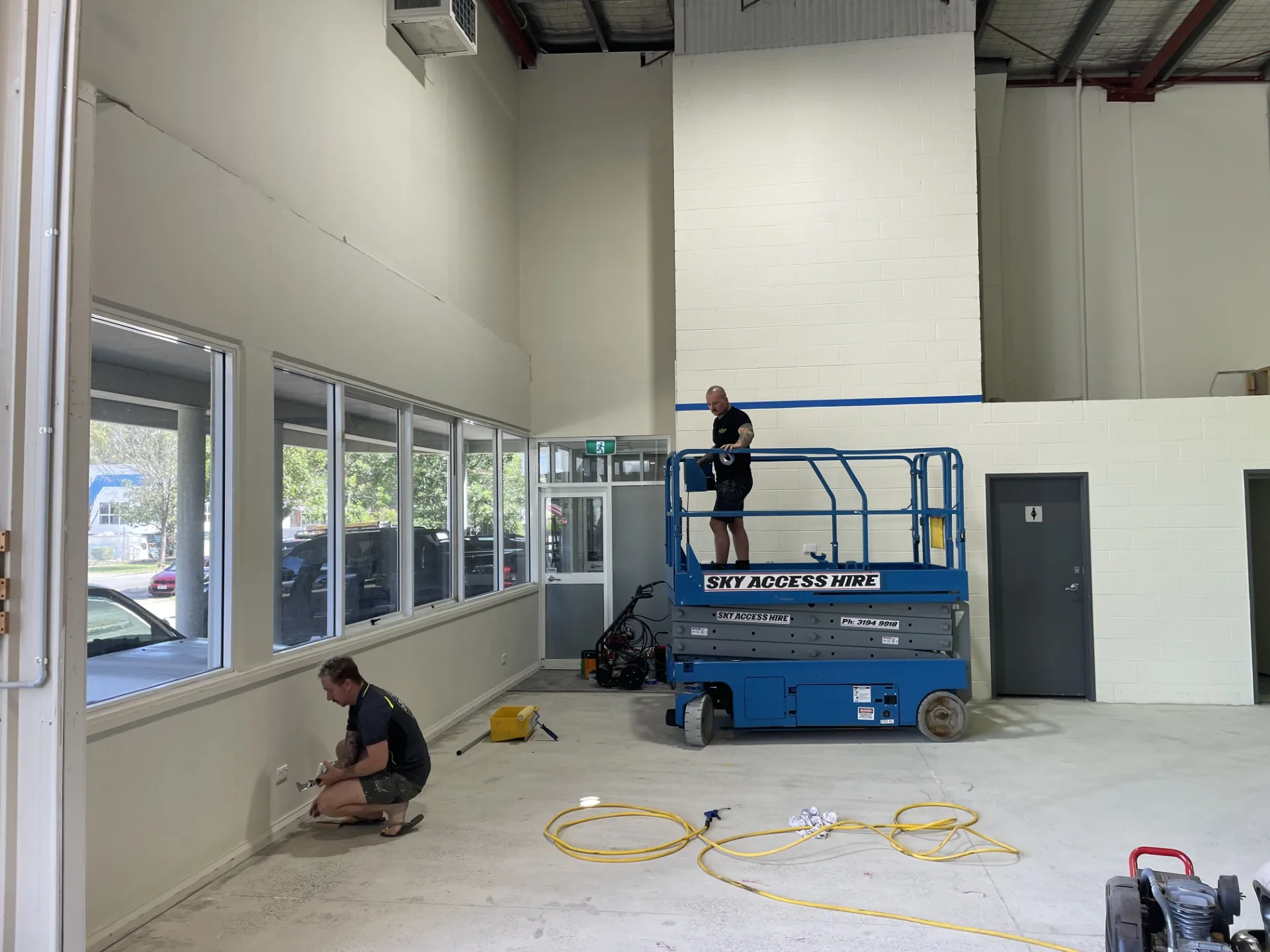 Painters working inside a large commercial workshop with fresh wall coatings